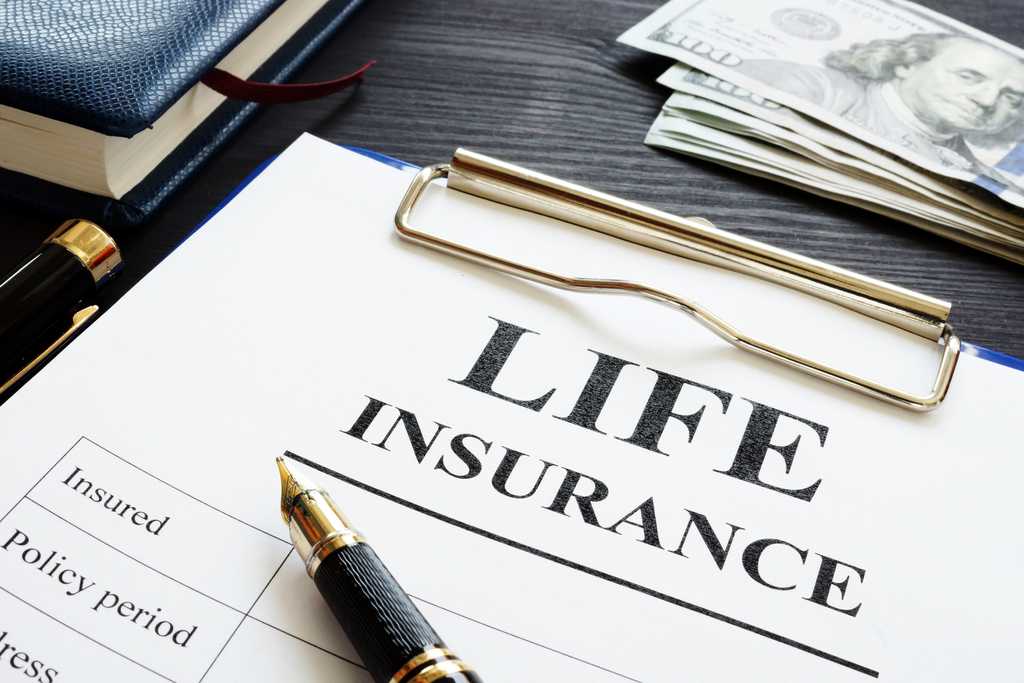 Clip board, pen, $100 bills and paper labeled Life Insurance